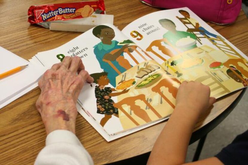 
Frankie Sanders, 89, helps Jesi Geier, 7, a student in Janie Stark Elementary’s Two Way...