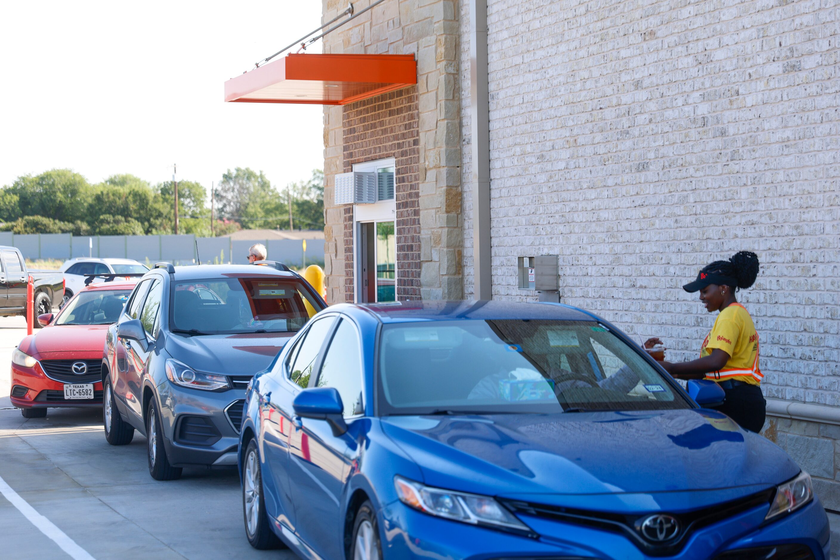 Employee Emike Anaani provides a drive-through order during the opening day of Bojangles in...