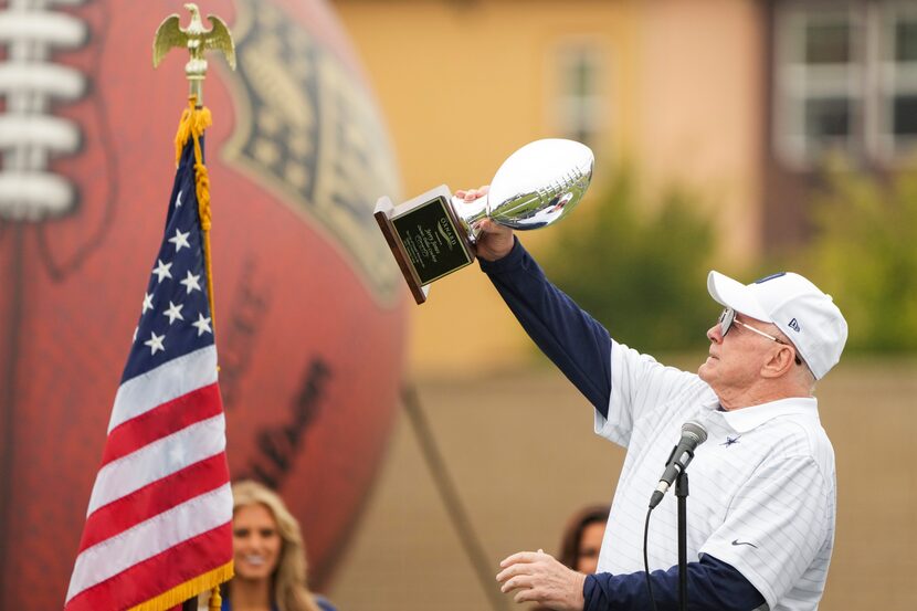 Dallas Cowboys owner and general manager Jerry Jones lifts a trophy presented to him by...