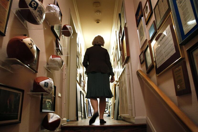 Alicia Landry walks down the hallway past some historical collections of her late husband,...