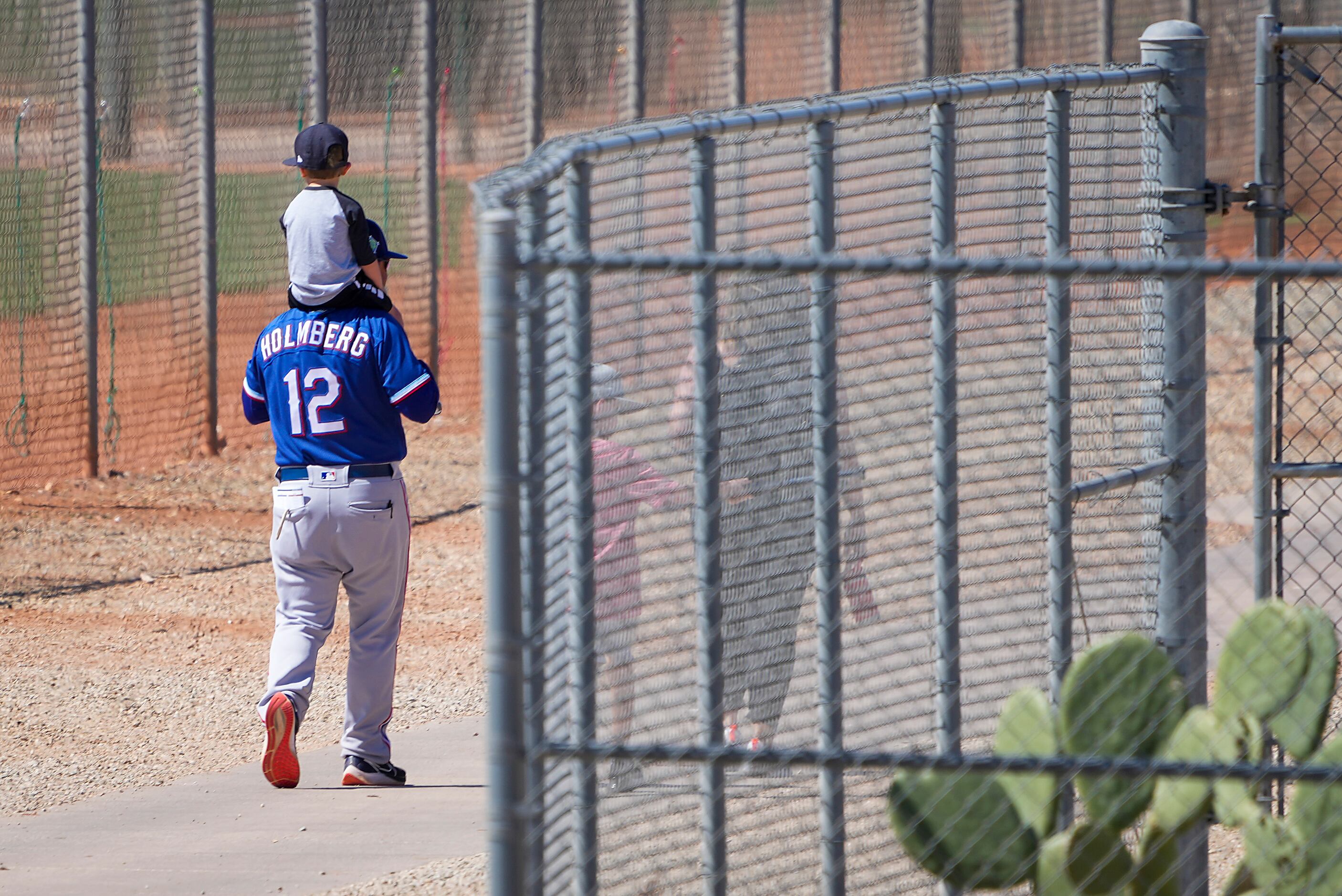 Texas Rangers minor league field coordinator Kenny Holmberg carries a child on his shoulders...