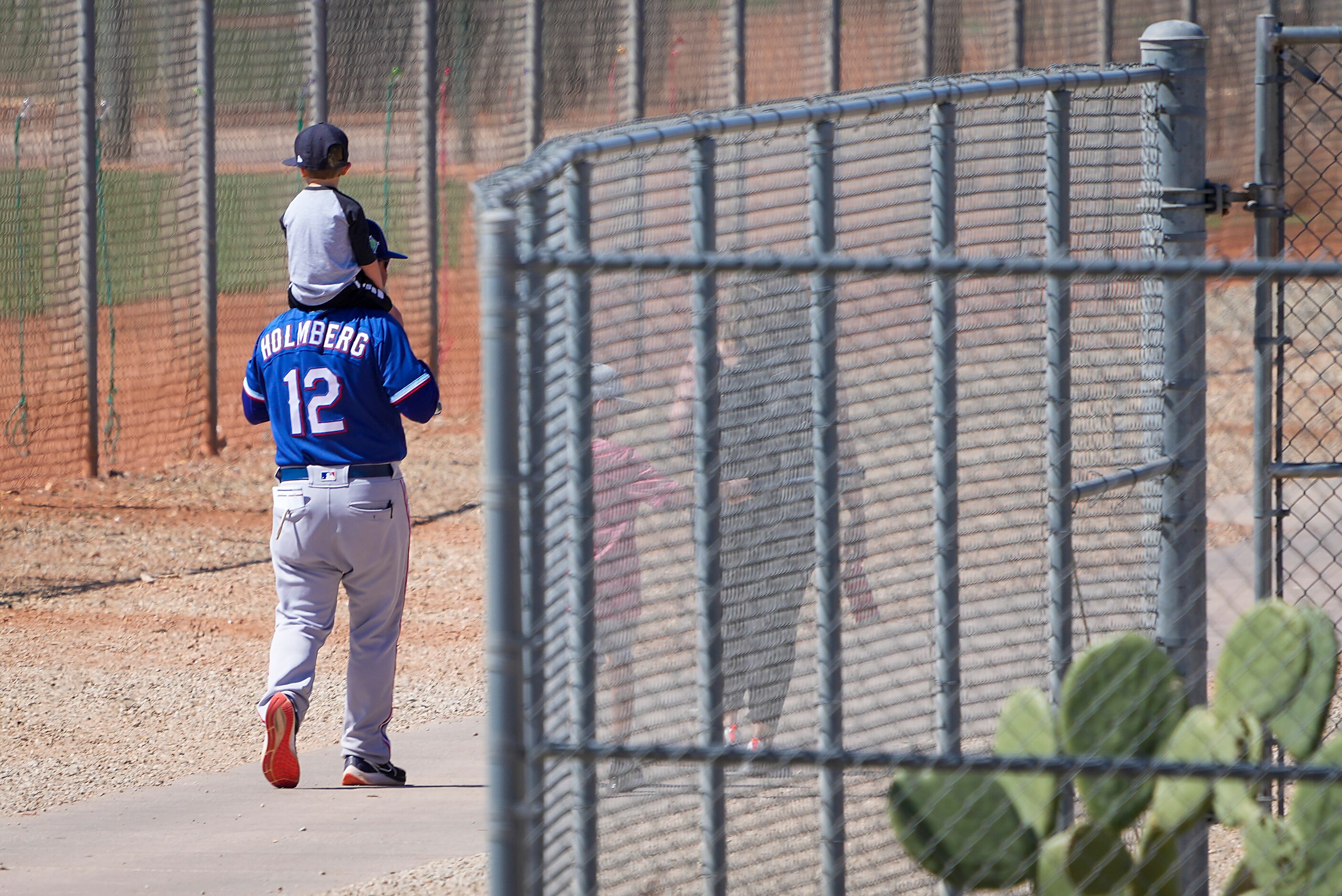 Texas Rangers minor league field coordinator Kenny Holmberg carries a child on his shoulders...