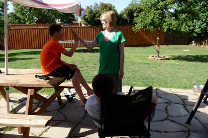 
Allyson Hendrickson high-fives her son, Cade, in the family's backyard in Flower Mound. For...