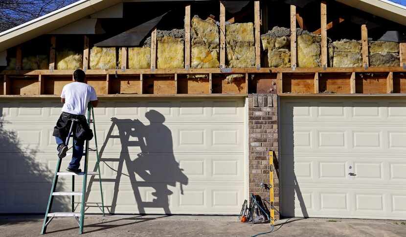 
Contractor Lucio Barriga repairs siding on a wall of Pastor Ron Adams’ house next to Ovilla...