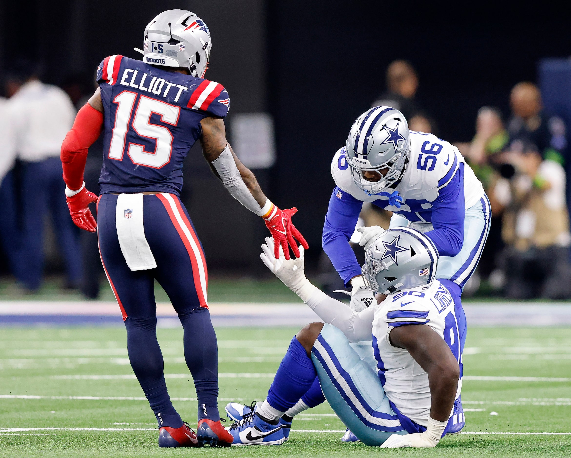 New England Patriots running back Ezekiel Elliott (15) entends a helping hand to former...