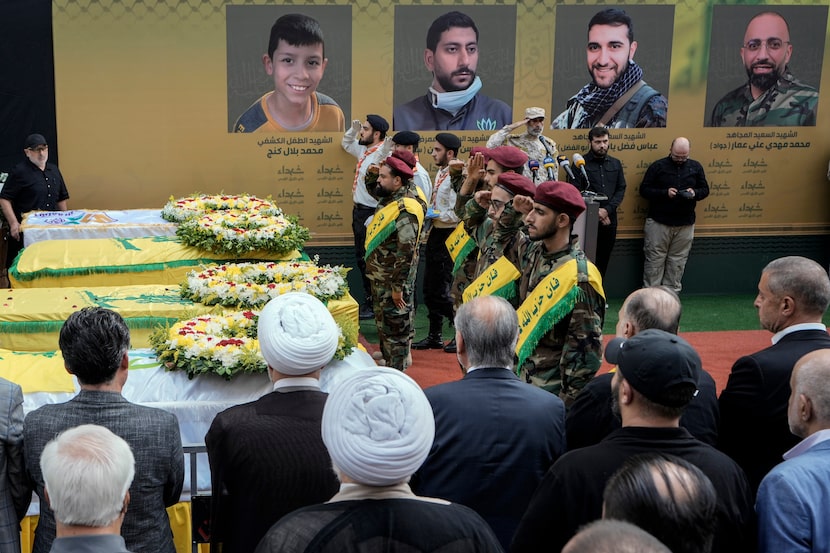 Hezbollah fighters salute as they stand next to the coffins of four victims who were killed...