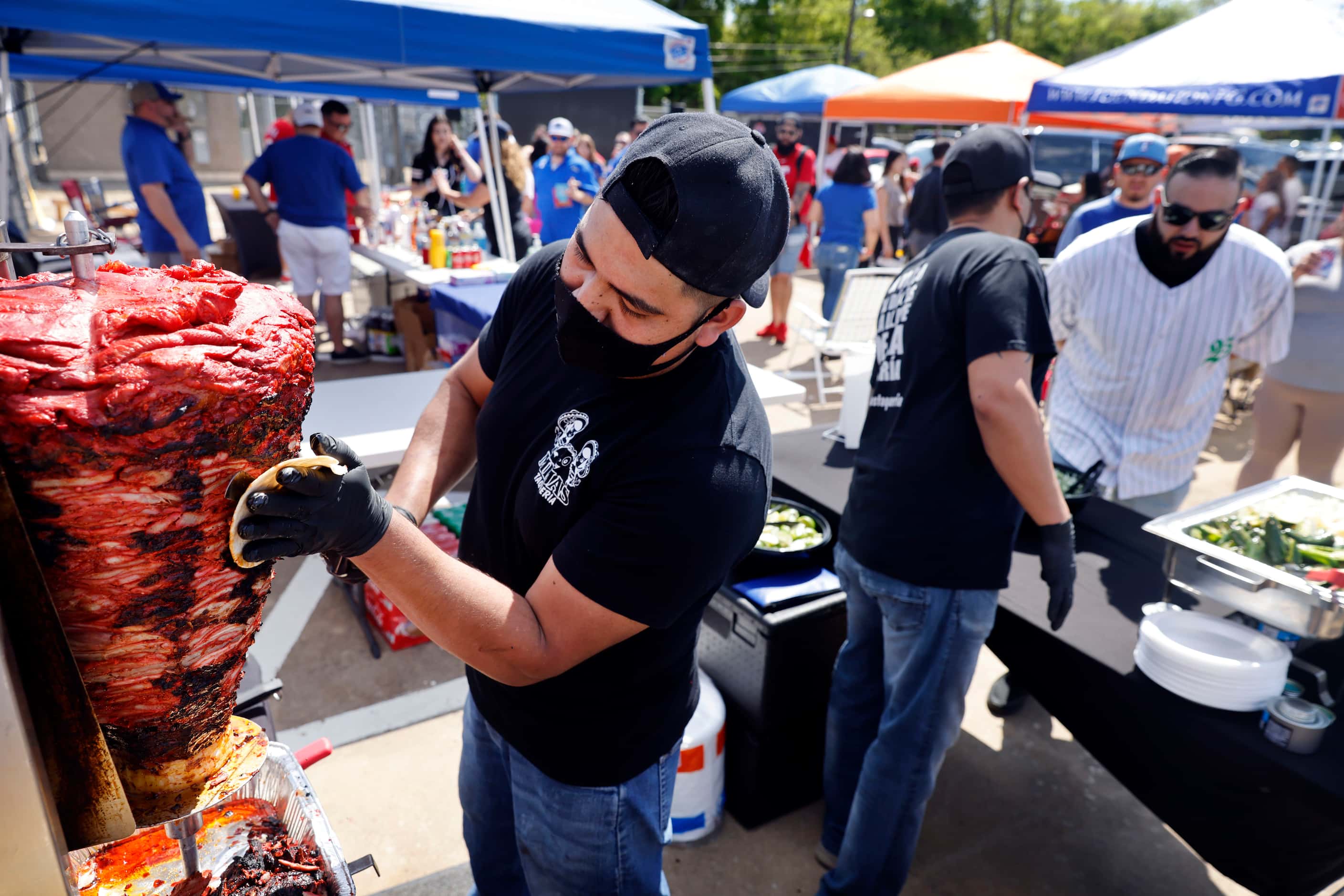 Saul Hernandez trims pork shoulder for Trumpo during an Opening Day tailgate party on...