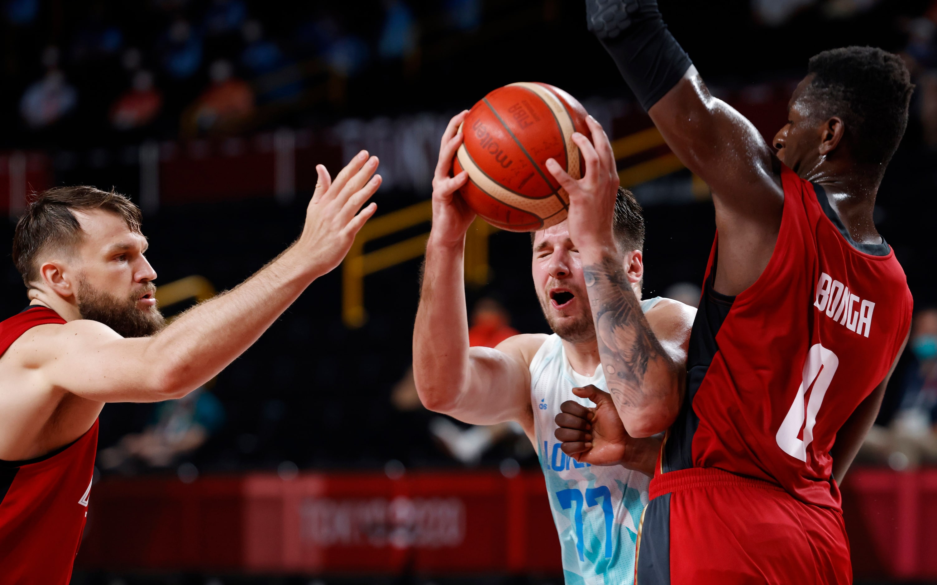 Slovenia’s Luka Doncic (77) drives in between Germany’s Danilo Barthel (22) and Isaac Bonga...