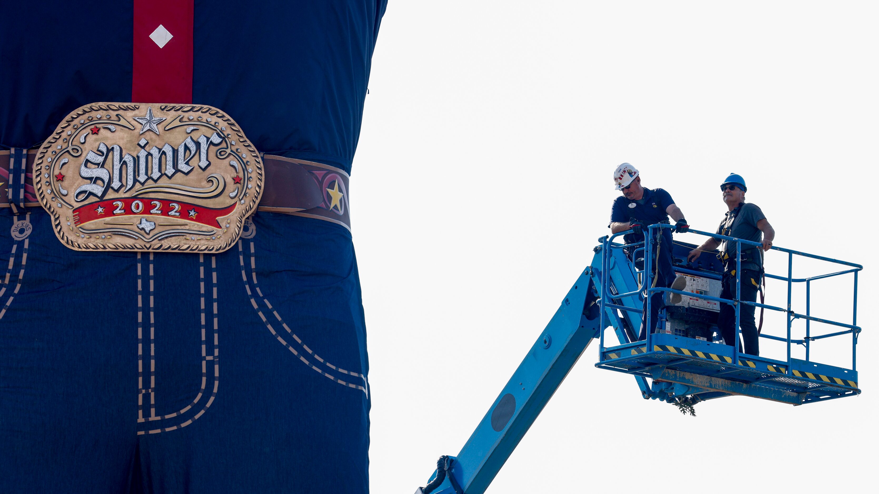 Crews ride in a lift to remove the steel cables used to lift Big Tex at The State Fair of...