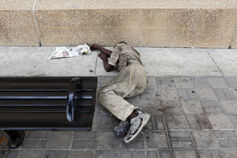 A homeless man stretched out in the shade behind the J. Erik Jonsson Central Library Tuesday...