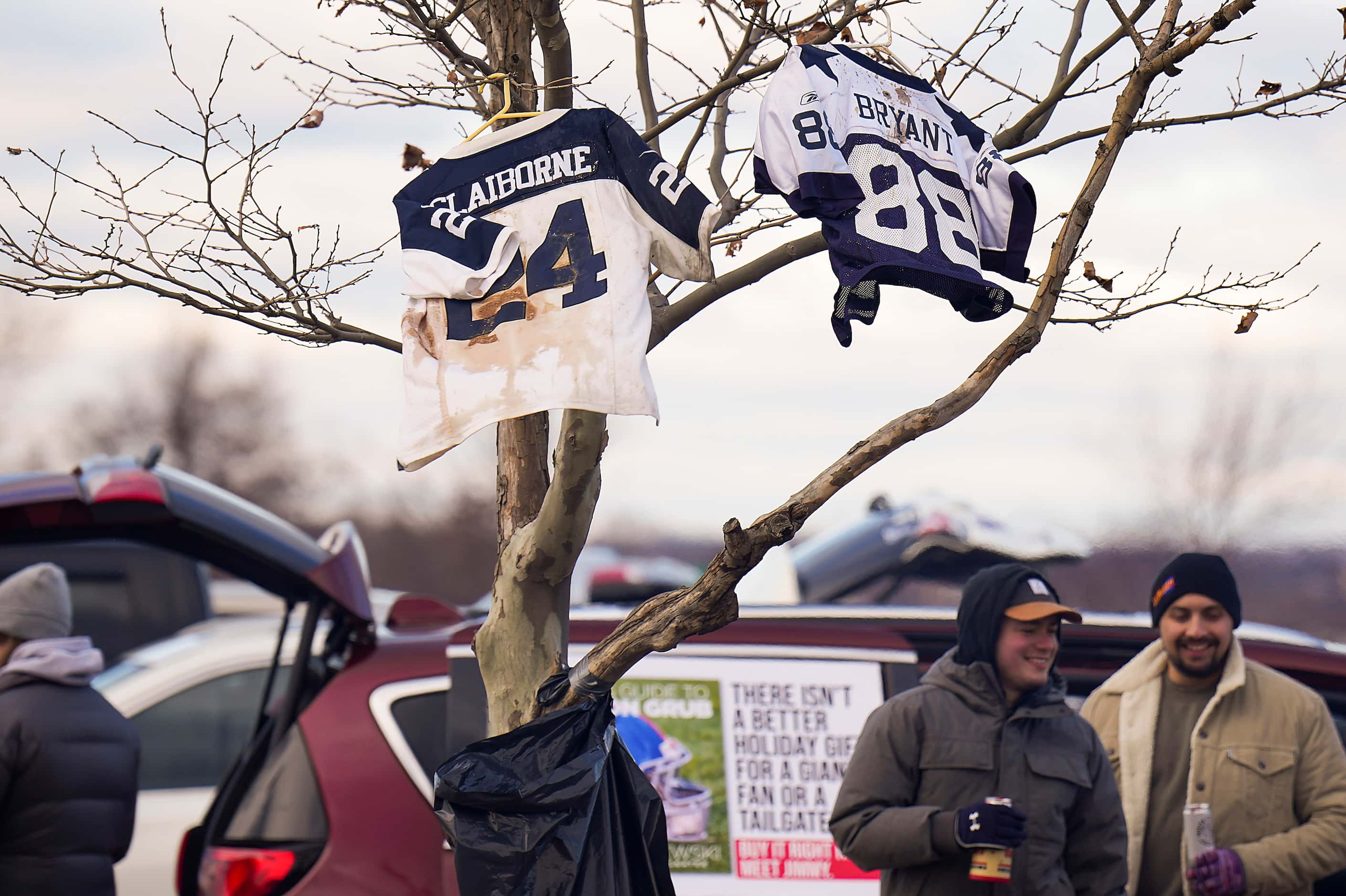 Dallas Cowboys jerseys hang from a tree as fans tailgate before an NFL football game between...