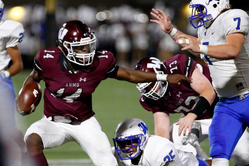 Wylie quarterback Rashad Dixon (14) fights for extra yards as he is hit by Plano East...
