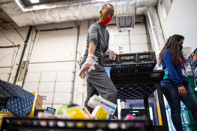 Dineo Gaofhiwe-Ingram drops a lice removal kit into a basket as she helps organize goods for...