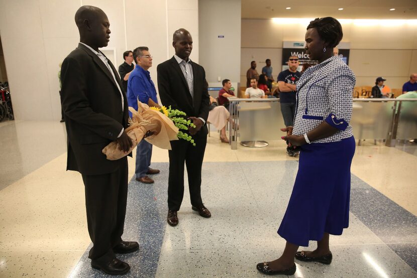 Abraham But (far left) and his cousin Philip Ayuen (center) pause to pray with But's mother...