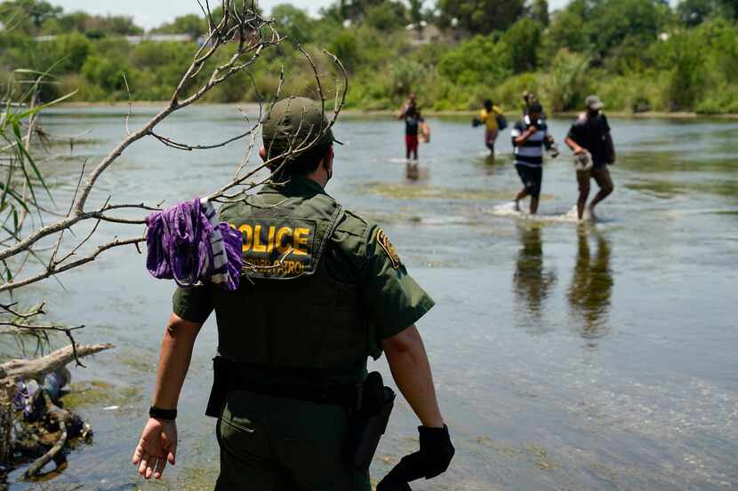 Un agente de la Patrulla Fronteriza de Estados Unidos observa a un grupo de migrantes cruzar...