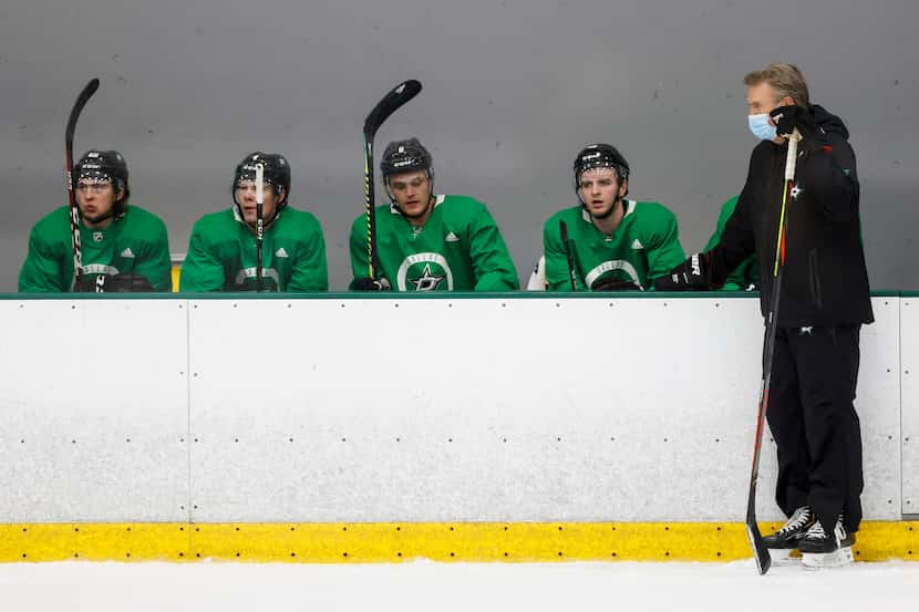 Stars head coach Rick Bowness watches his team work out alongside defensemen (from left)...