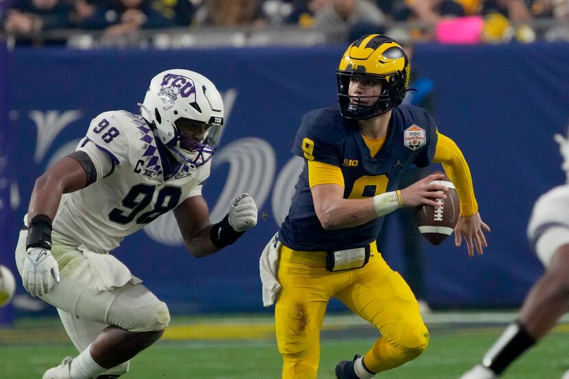 Michigan quarterback J.J. McCarthy (9) trees to elude TCU defensive lineman Dylan Horton...