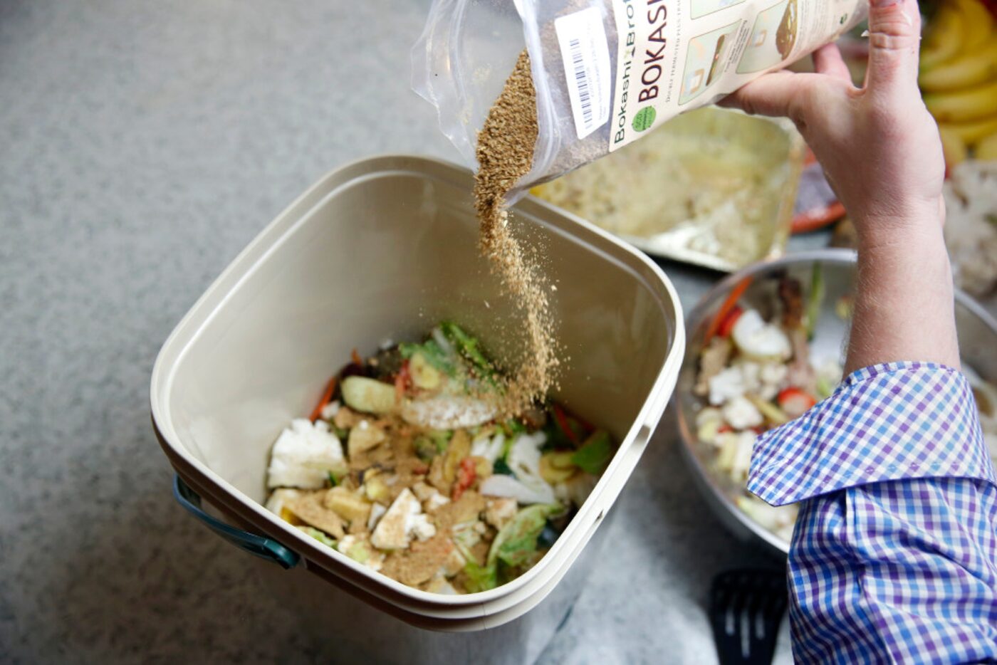 Horticulturalist Daniel Cunningham pours a layer of bokashi bran used to ferment food scraps.