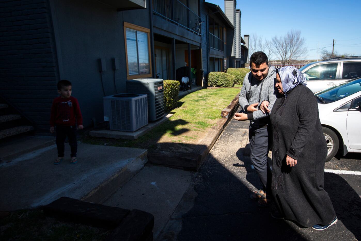 Abduljalil Jawish walks his mother Kadria Kharzoum to the apartment he shares with his...