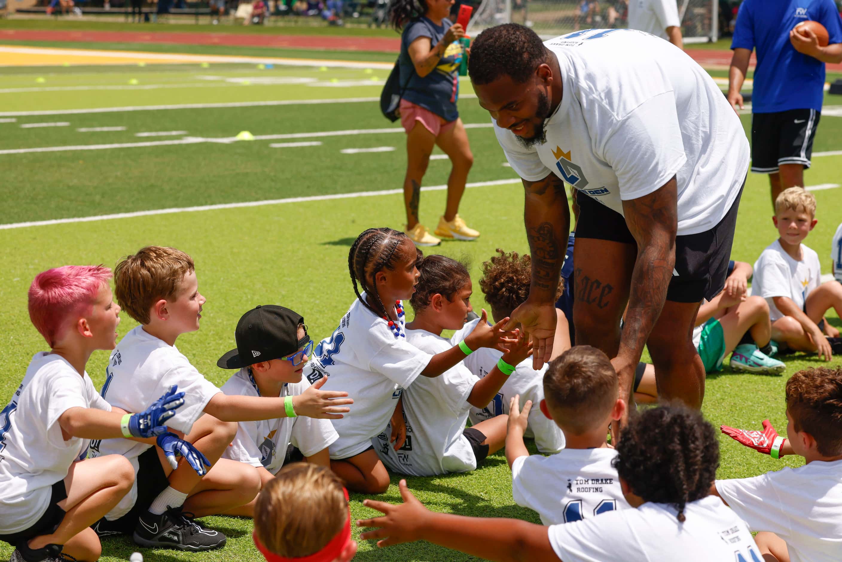 Dallas Cowboys linebacker Micah Parsons high-fives young football players at his youth...