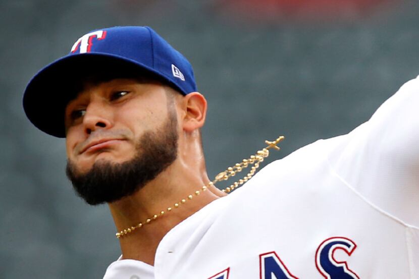 Wearing a gold rosary, Texas Rangers starting pitcher Martin Perez (33) throws in the first...