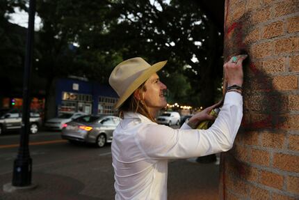 Grant English scrubs a graffiti tag off the side of a building. Activists were trying to...