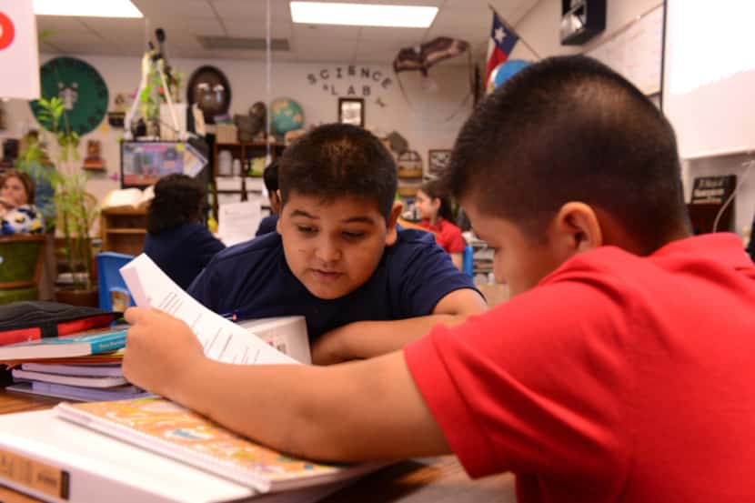 Fifth-grade students Jose Saavedra (left) and Ulisses Salto read an assignment at...