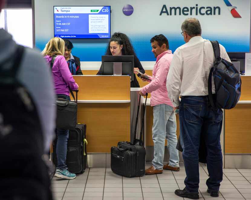 Passengers line up at an American Airlines ticket counter at DFW International Airport in...