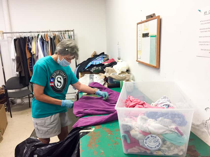 An RSVP volunteer folds clothes on a table.