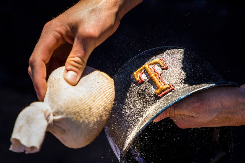 exas Rangers infielder/outfielder Drew Robinson puts pine tar and rosin on his helmet before...