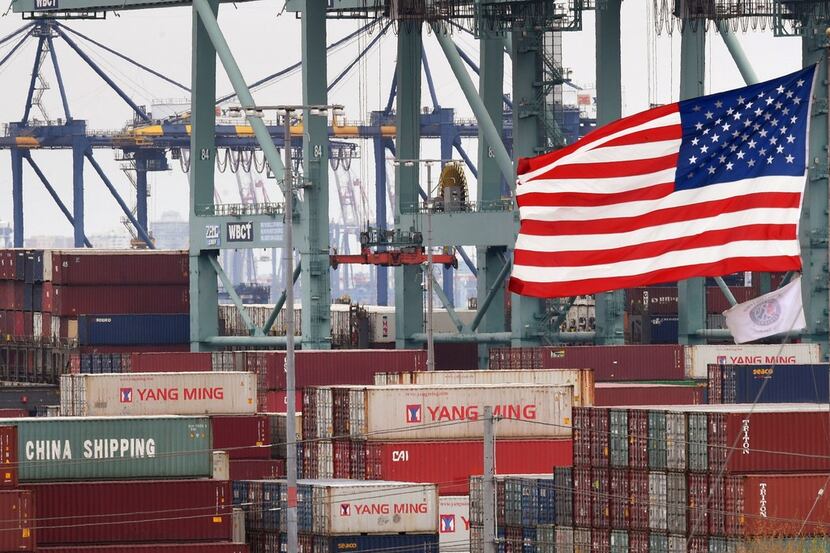 Chinese shipping containers are stored beside a U.S. flag after being unloaded at the Port...