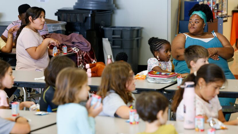 Coordinator Brandi Reed (top right) watches over children during snack time at Dallas City...