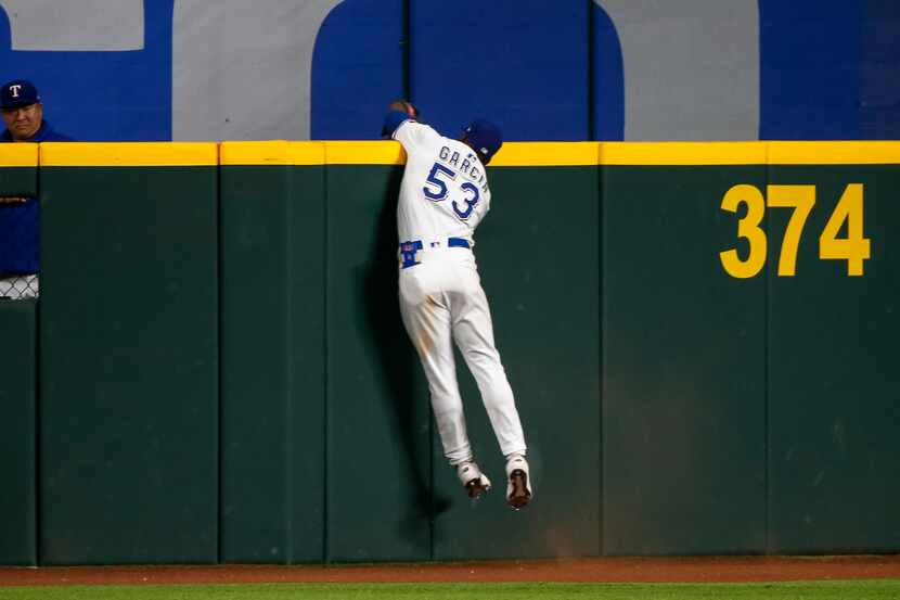 Texas Rangers right fielder Adolis Garcia (53) makes a leaping catch over the outfield wall...