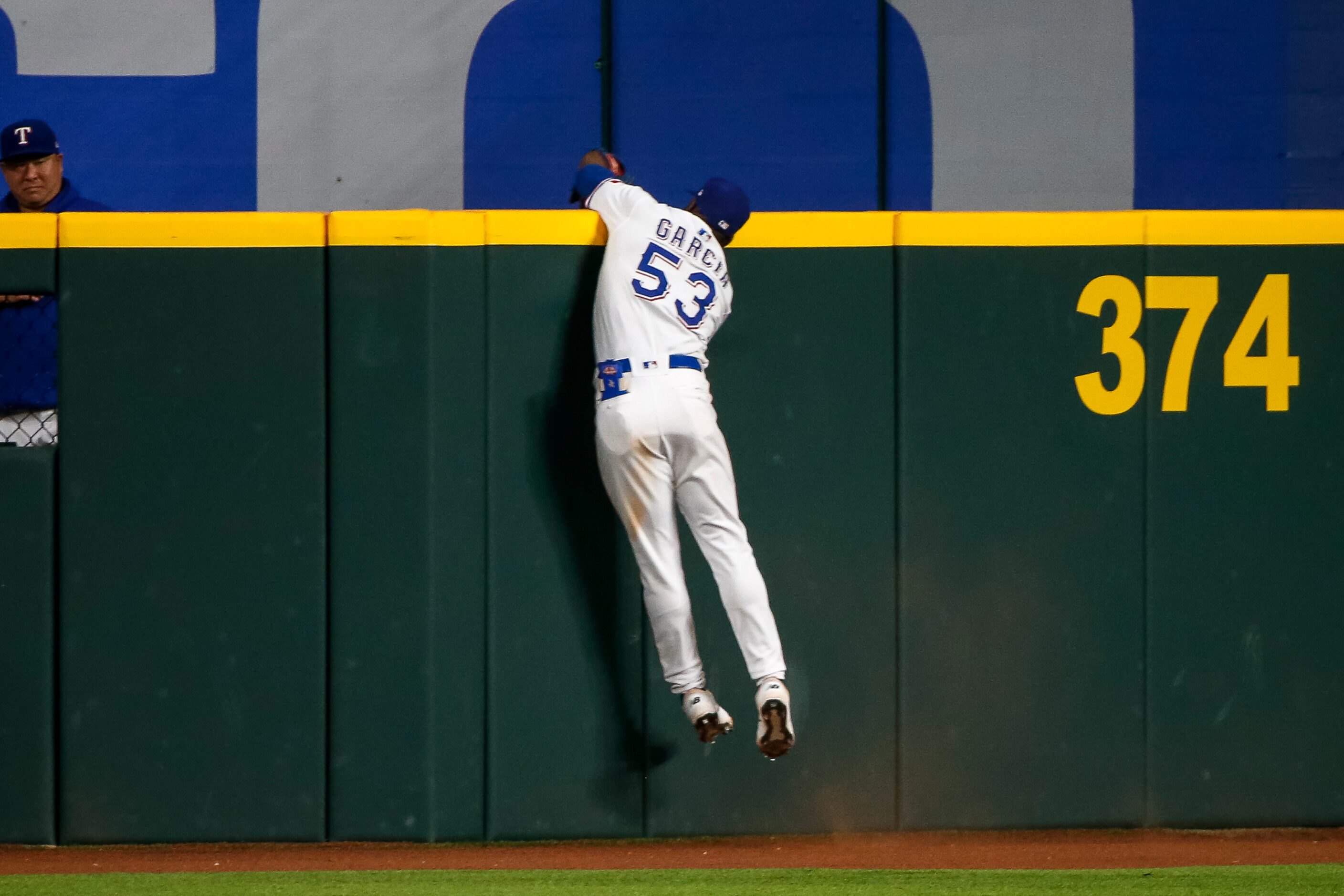 Texas Rangers right fielder Adolis Garcia (53) makes a leaping catch over the outfield wall...