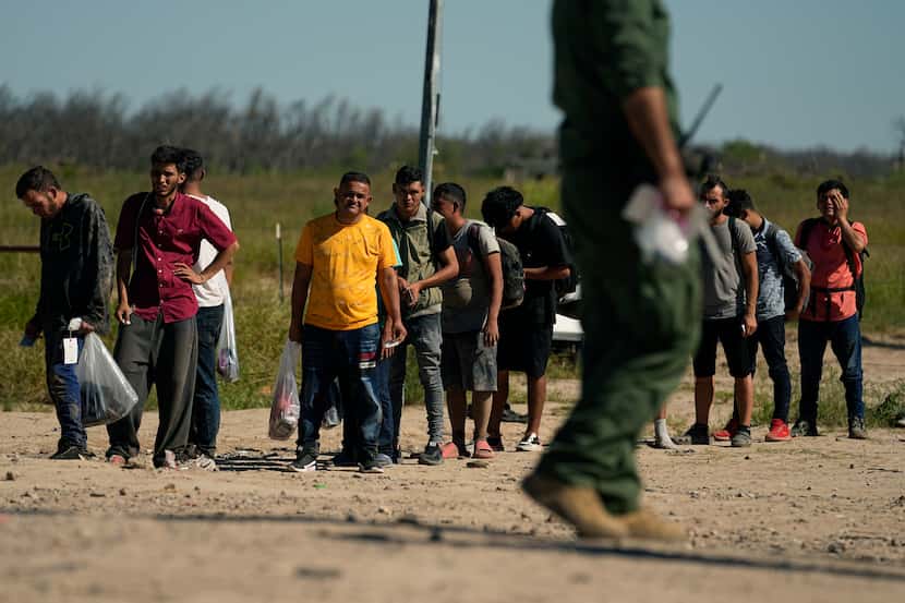 Migrants wait to be processed by the U.S. Customs and Border Patrol after they crossed the...