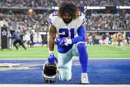 Dallas Cowboys running back Ezekiel Elliott kneels on the field before an NFL football game...
