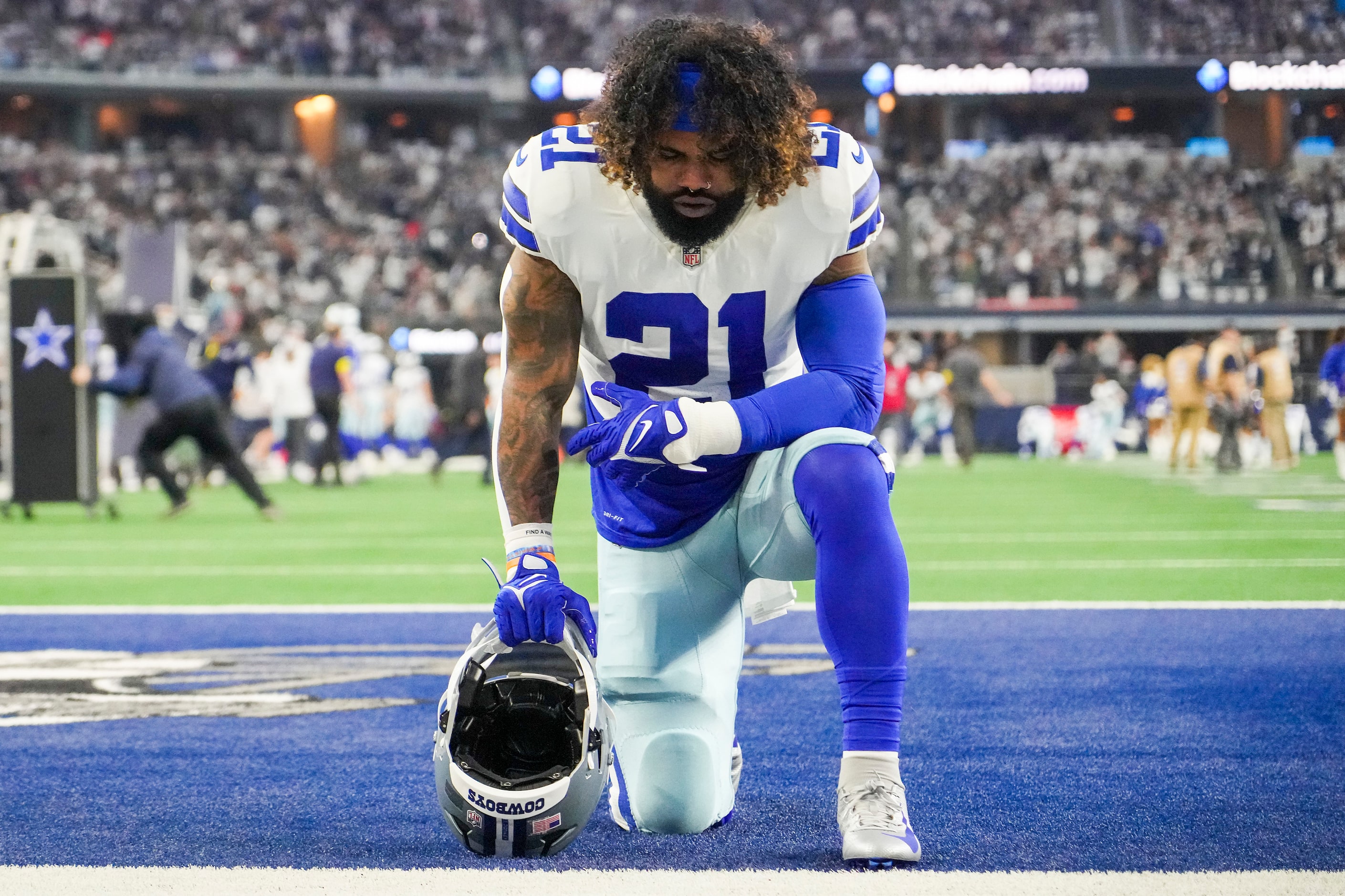 Dallas Cowboys running back Ezekiel Elliott kneels on the field before an NFL football game...