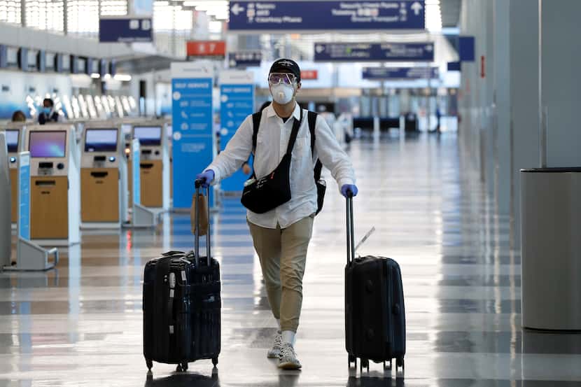 A traveler wears a mask and protective goggles as he walks through Terminal 3 at O'Hare...