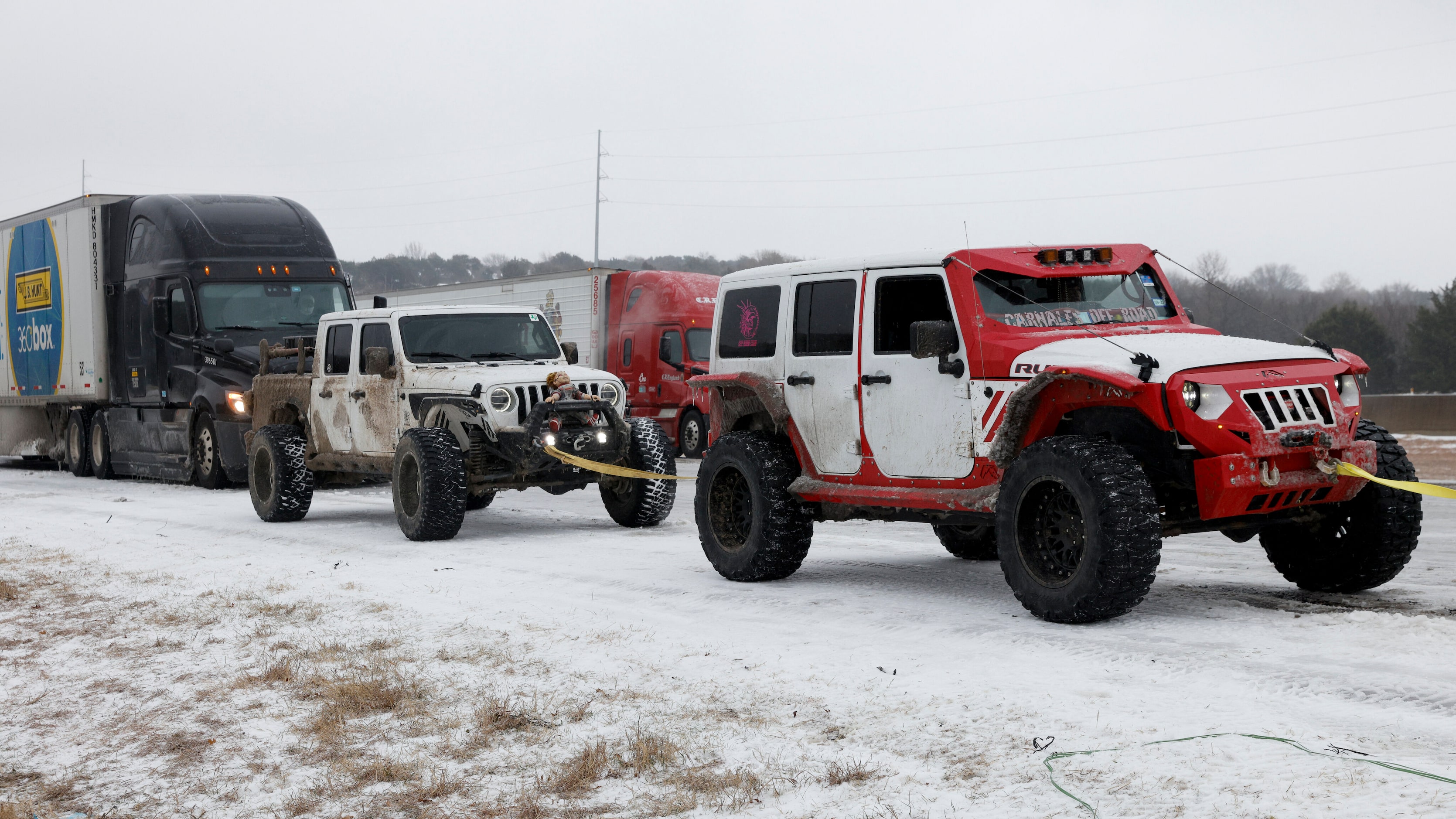 Members of the Carnales Off Road Jeep club work to pull a semi-truck up an ice covered hill...