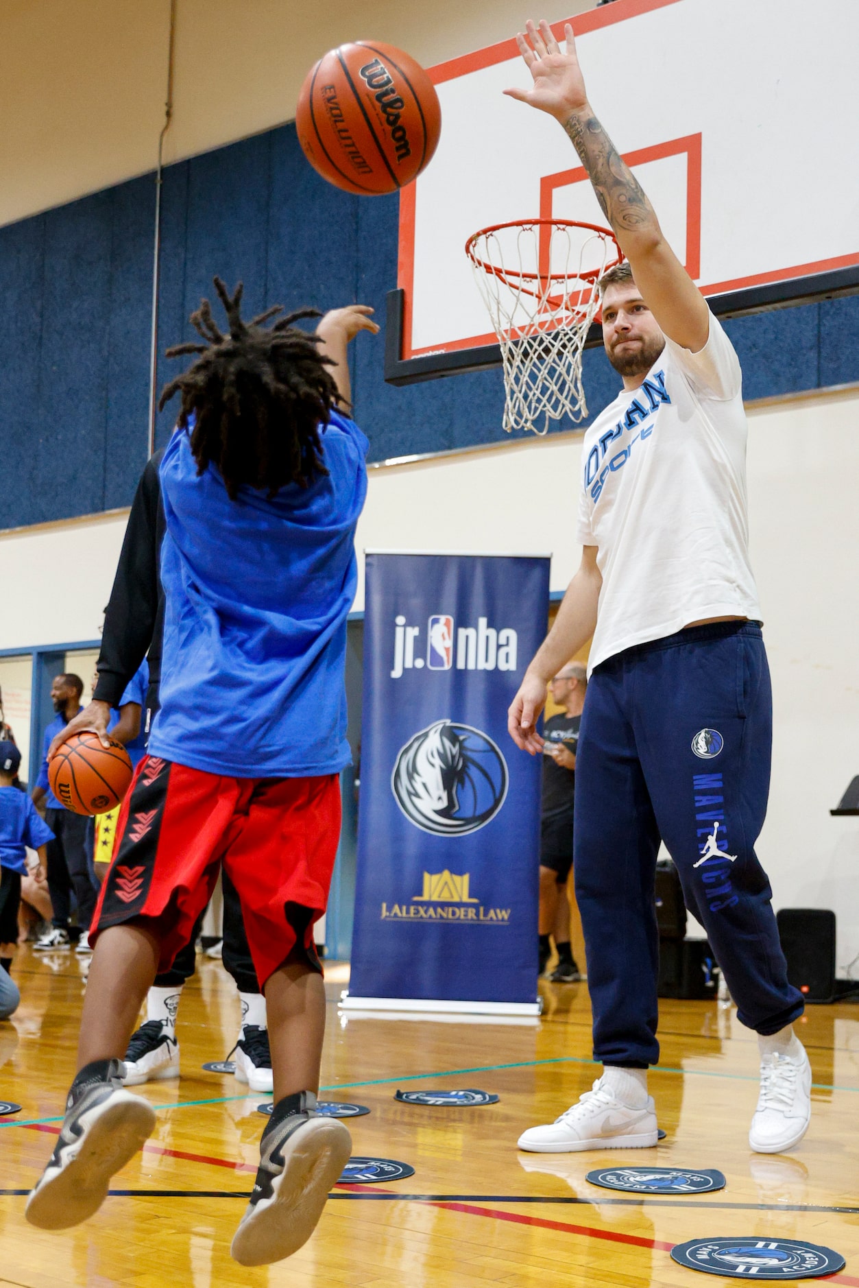 A child shoots over Dallas Mavericks guard Luka Doncic during a children’s basketball...