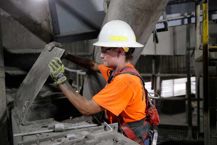 Carsyn Garcia lifts a cover to check the flow of materials at the Martin Marietta cement...