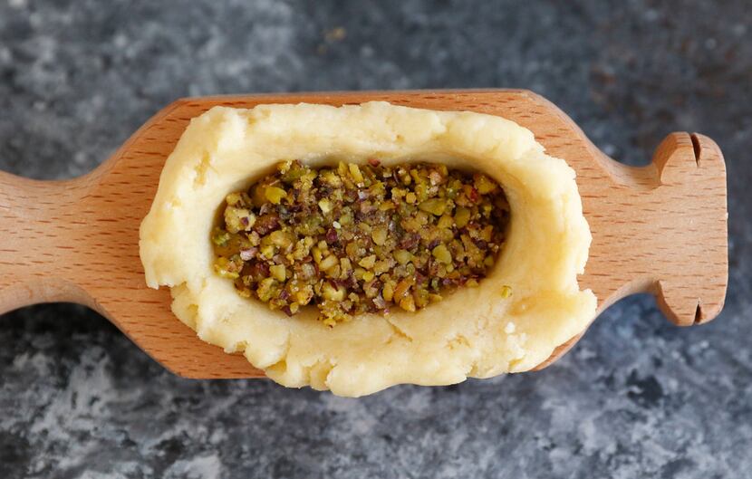 Dough is pressed into an oval mold, then stuffed with pistachio filling. 