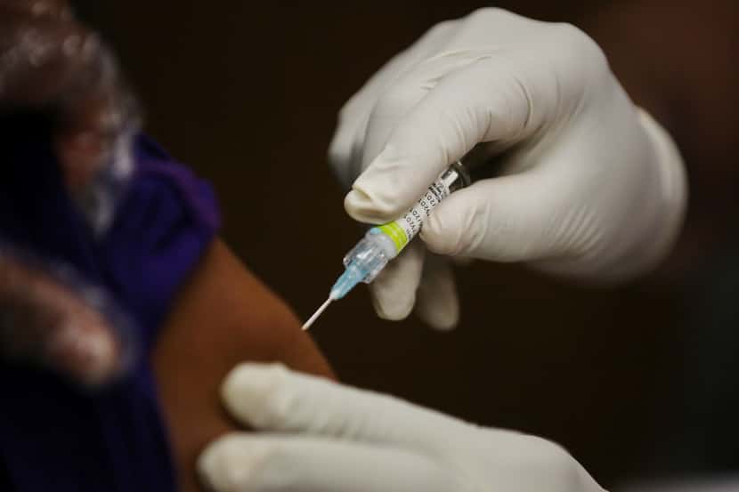 Chiedu Eleda, a licensed practical nurse, administers an influenza vaccine at a mobile...