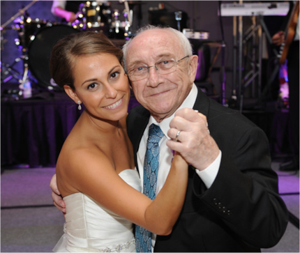 Young woman in wedding dress dancing with elder gentleman in suit and tie at a wedding.