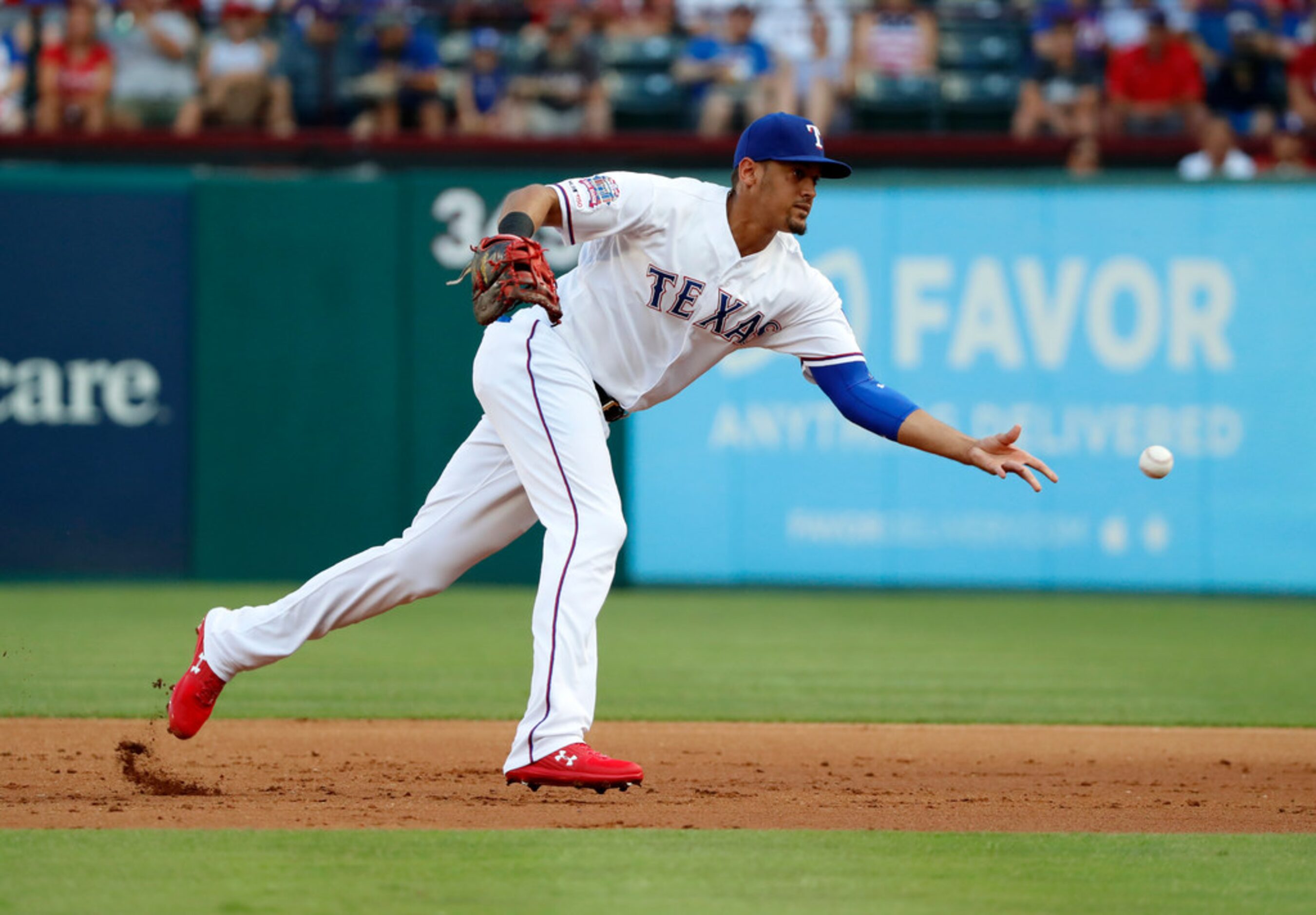 Texas Rangers first baseman Ronald Guzman flips the ball to starting pitcher Ariel Jurado at...