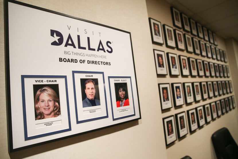 Photos of the VisitDallas board of directors fill a conference room wall during a press...