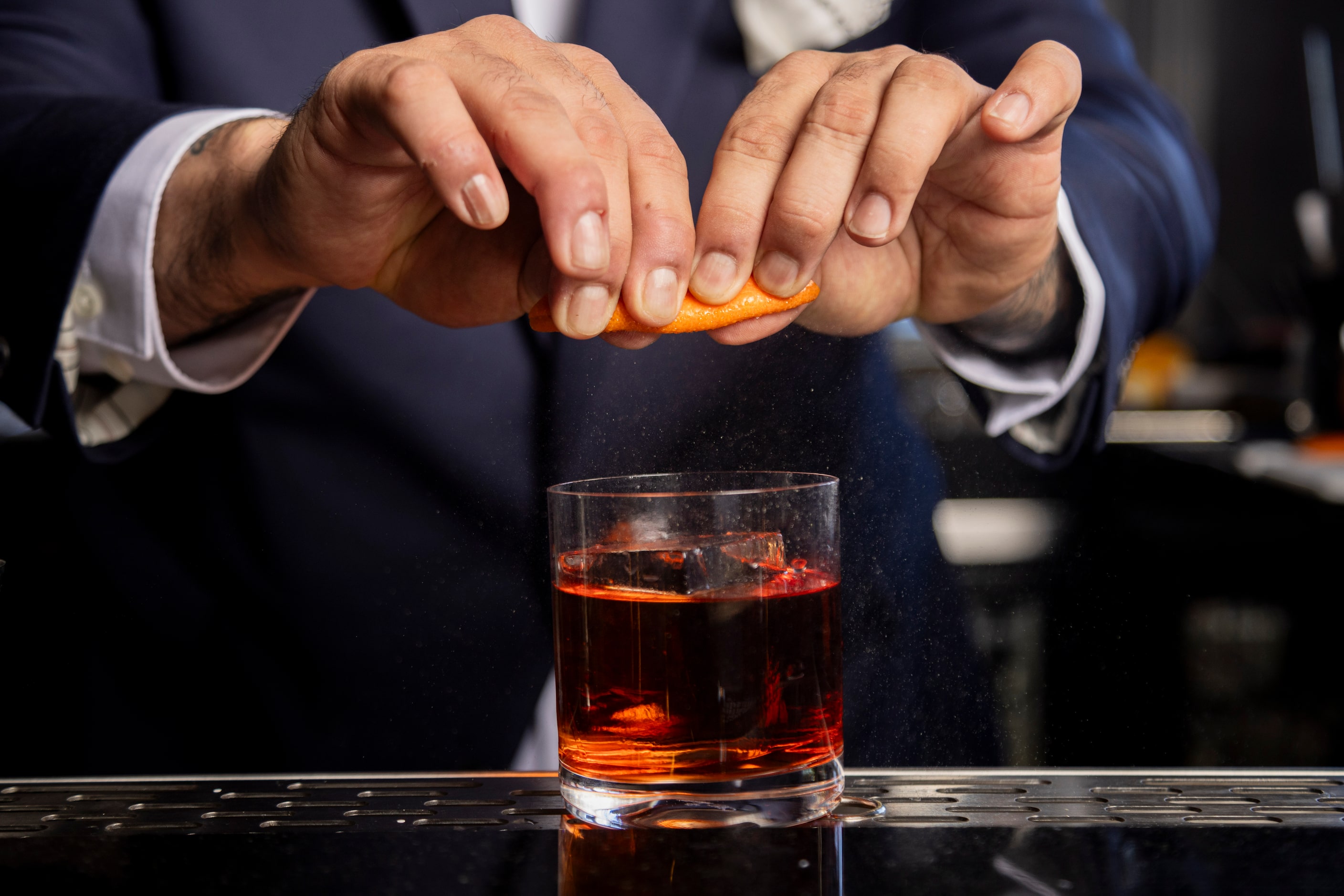 Beverage director Ravinder Singh spritzes an orange as he prepares the Truffle Negroni...