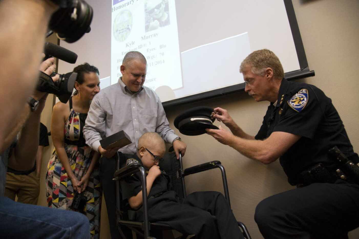 Kyle Murray, 10, gets a police hat from Frisco Police Chief John Bruce, who made the...