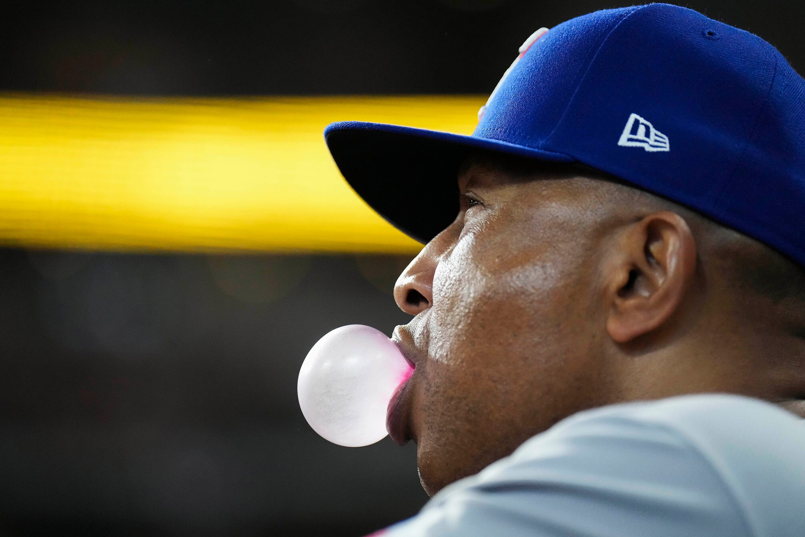 Texas Rangers third base coach Tony Beasley blows a bubble in the dugout during the seventh...