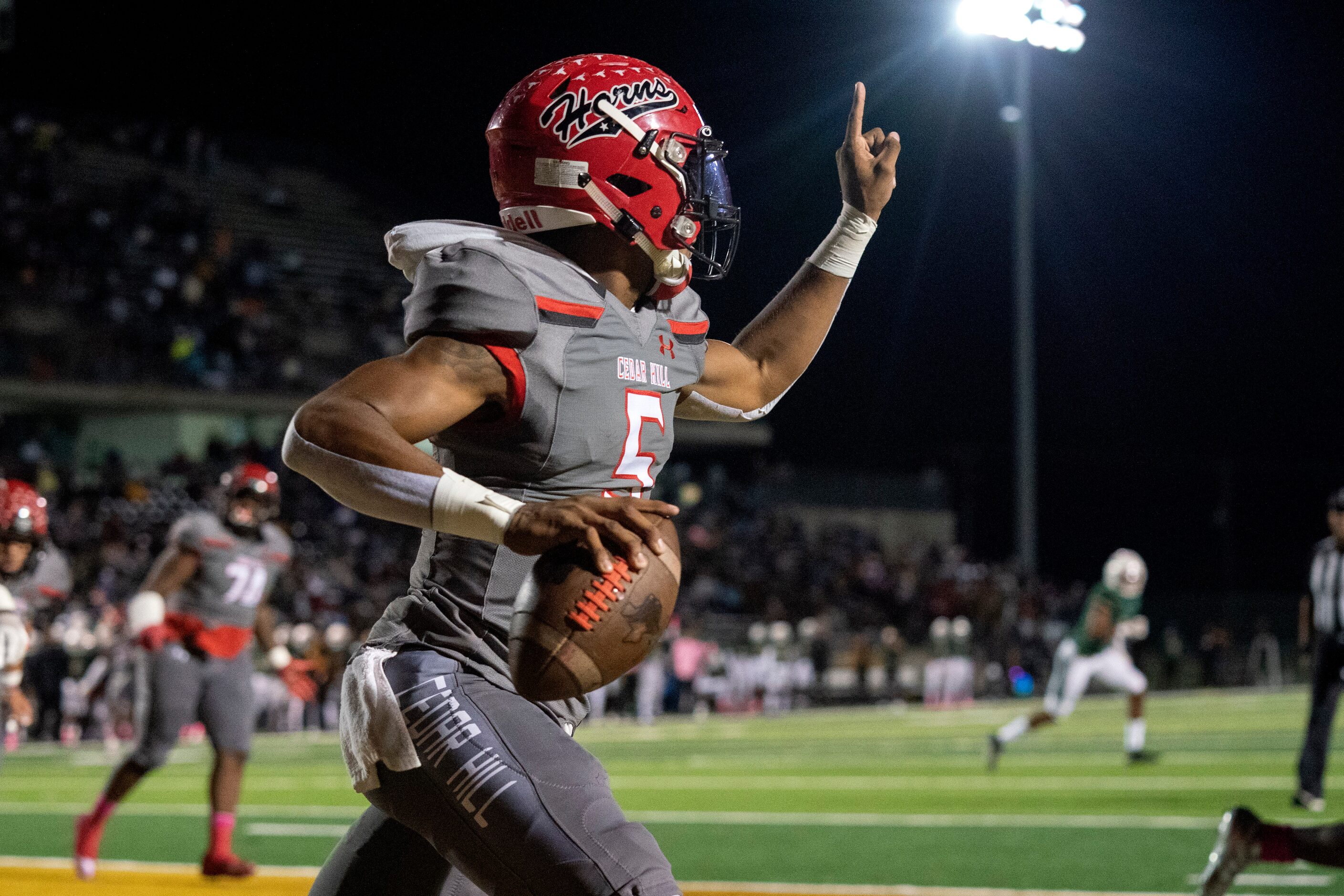 Cedar Hill junior quarterback Cedric Harden, Jr. (5) signals to a receiver as he scrambles...